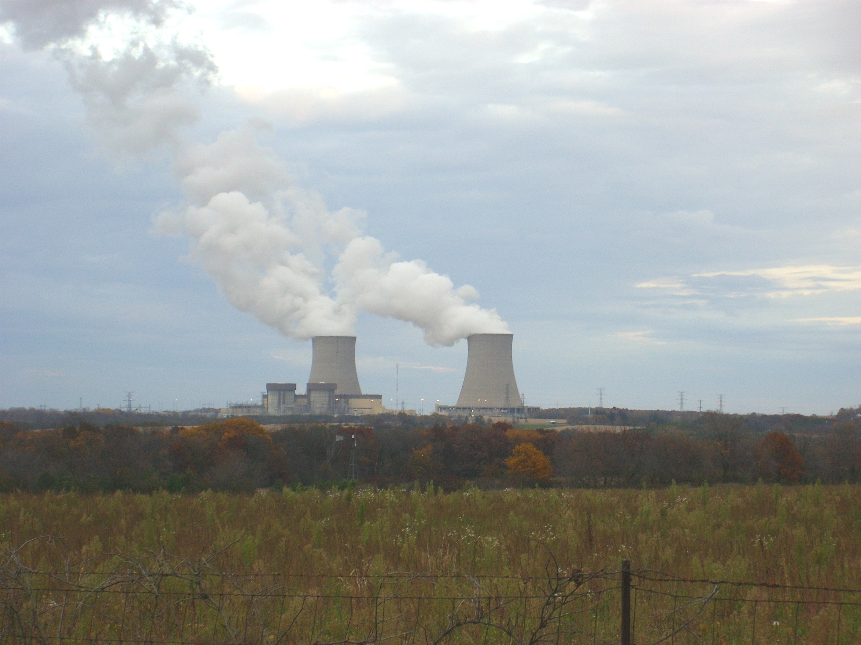 Two cooling towers releasing steam at Byron Nuclear Generating Station beyond an Illinois field